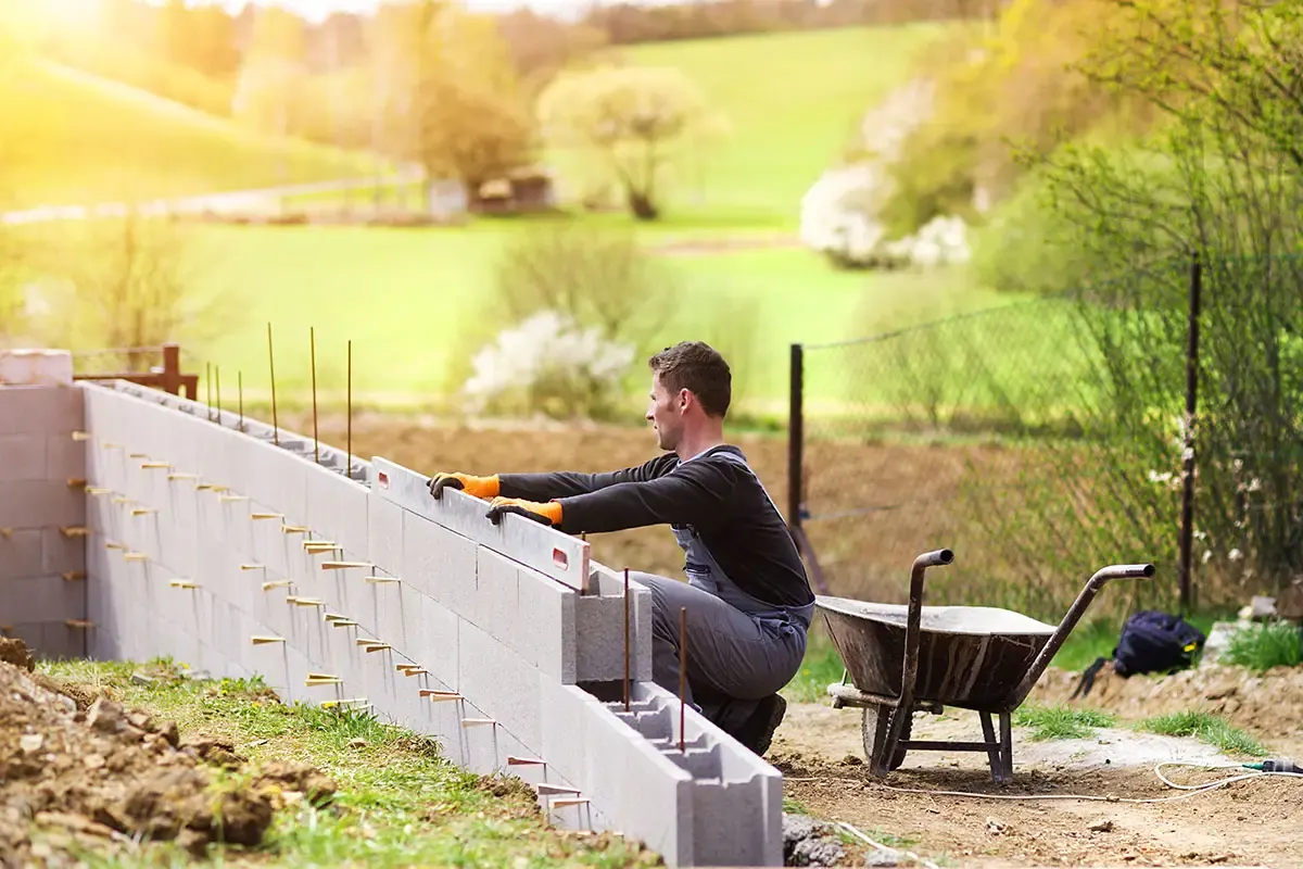 Block retaining wall being laid course by course on a sloping site